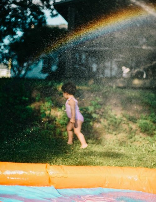 child near wading pool and rainbow