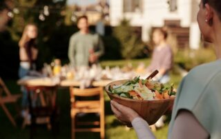 woman carrying bowl of salad to backyard block party