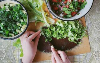 woman's hands chopping herbs on cutting board