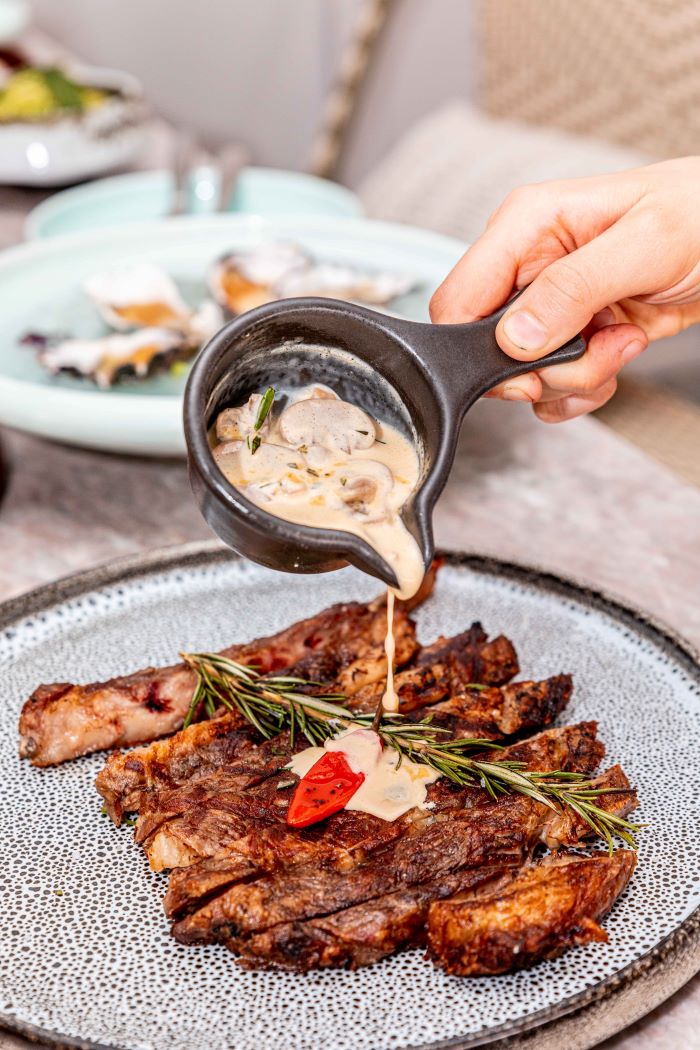 pouring sauce onto steak