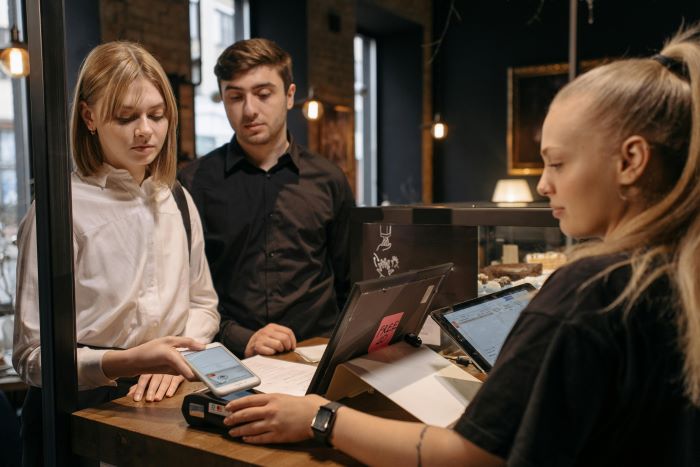 Young Adults at Cafe tipping Server