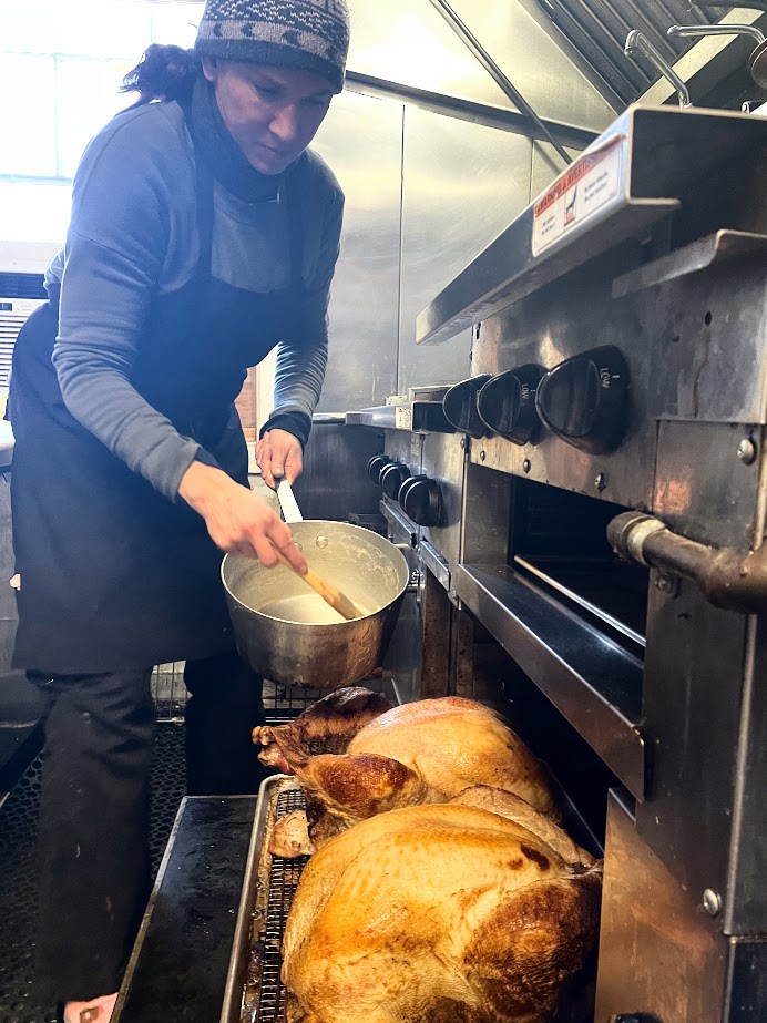 Chef basting turkeys in oven